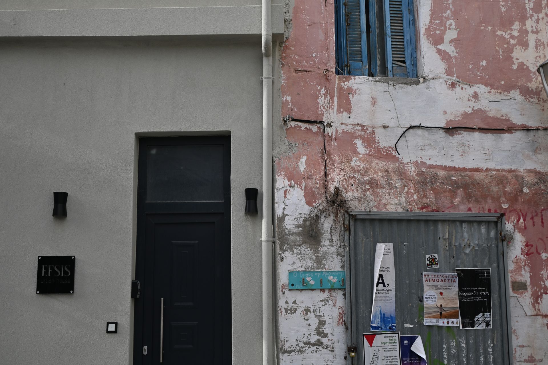 Dark doorway in a smooth grey facade beside a weathered pink wall